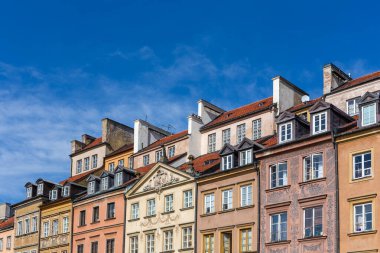 Polonya 'nın Varşova kentindeki Eski Kent Pazar Meydanı' ndaki (Rynek Starego Miasta) eski evlerin renkli cepheleri ve kiremitli çatıları, arka planda mavi gökyüzü, kopyalama alanı.