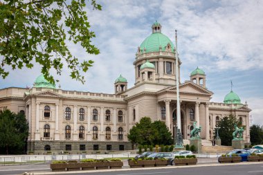 Belgrad, Sırbistan, 08.07.22. Sırbistan Cumhuriyeti Ulusal Meclisi, Belgrad, yeşil kubbeli neo-barok mimari tarzı, King Alexander Bulvarı caddesinde arabalar, yaz manzaralı.
