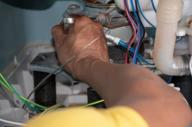 Teknisyen çamaşır makinesini tamir ediyor.