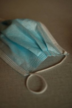 Bir tıbbi mavi maske loş ışıkta masada.