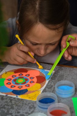 Renkli kumdan yapılmış bir mandala, kızların annesi.