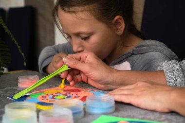 Renkli kumdan yapılmış bir mandala, kızların annesi.