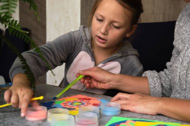 Renkli kumdan yapılmış bir mandala, kızların annesi.