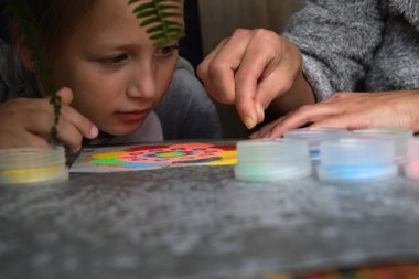 Renkli kumdan yapılmış bir mandala, kızların annesi.