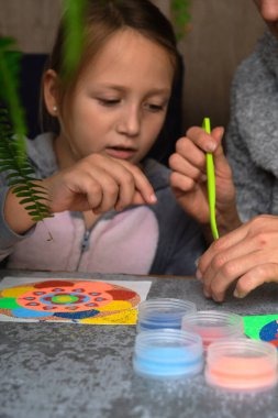 Renkli kumdan yapılmış bir mandala, kızların annesi.