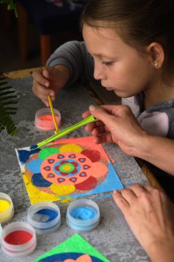 Renkli kumdan yapılmış bir mandala, kızların annesi.