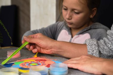 Renkli kumdan yapılmış bir mandala, kızların annesi.
