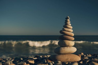 Sahilde deniz manzaralı taşlardan oluşan dengeli bir piramit.