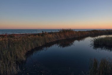 Gün batımında göldeki sakin su manzarası uzak dağlarda