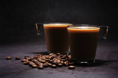 iki fincan sütlü kahve ve dağınık kahve çekirdeği.