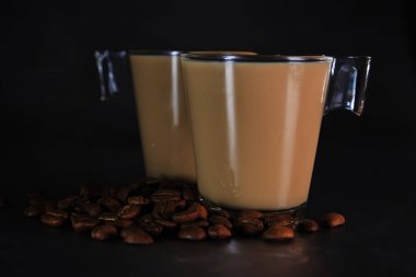 iki fincan sütlü kahve ve dağınık kahve çekirdeği.