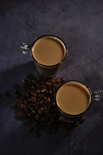 Dos tazas de café con leche y granos de café dispersos —  Fotos de Stock