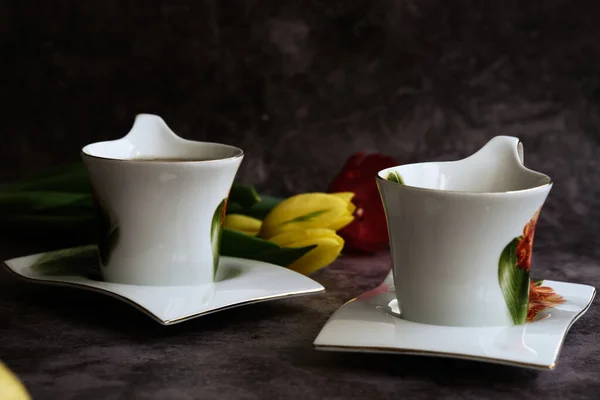 Dwie białe filiżanki herbaty i żółte i czerwone tulipany — Zdjęcie stockowe