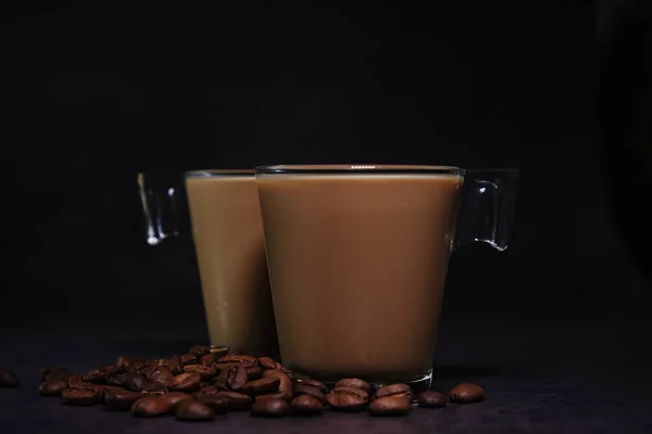 Duas xícaras de café com leite e grãos de café espalhados — Fotografia de Stock
