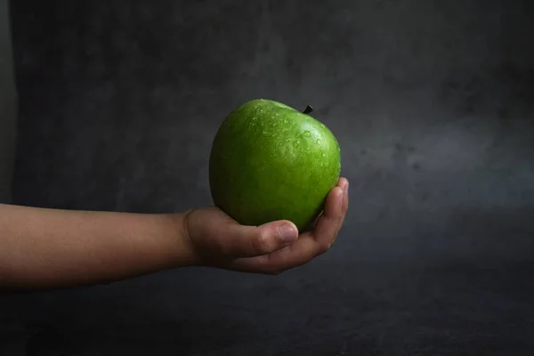 La fille tient une pomme verte dans sa main — Photo