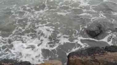 Denizin sakin dalgaları kayalara çarpıyor.