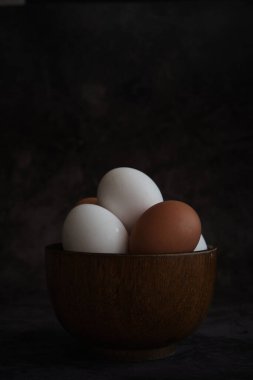 Beyaz ve kahverengi tavuk yumurtaları kasede.