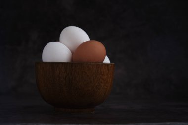 Beyaz ve kahverengi tavuk yumurtaları kasede.