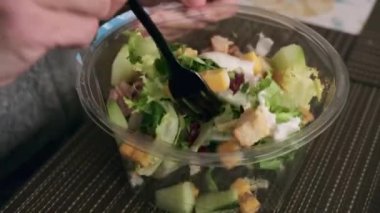 Bir çatalla taze yeşil salatayı karıştırıyor.
