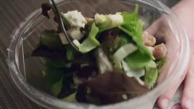 Bir çatalla taze yeşil salatayı karıştırıyor.