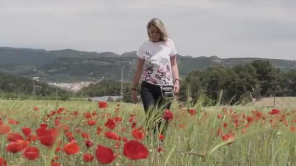 Una chica camina a través de un campo de amapola — Vídeos de Stock