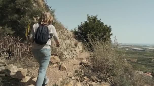 Una mujer camina sobre una montaña rocosa — Vídeos de Stock