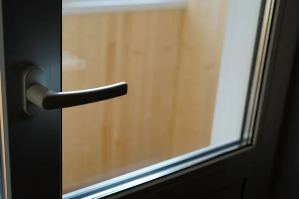 The plastic door to the balcony is slightly ajar. In the background, a wall lined with wood.