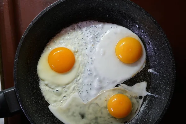 在煎锅里煎鸡蛋 黄色的蛋黄从顶部看问题 — 图库照片