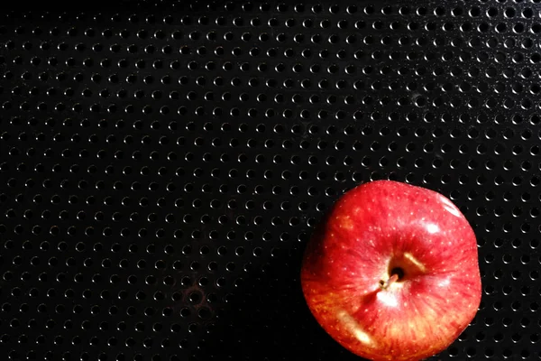 Red Apple on a black background. Half-light and a brightly lit Apple.