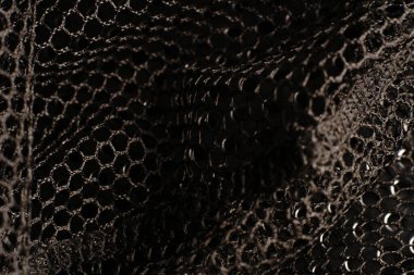 Siyah doku. Siyah bir ağ siyah delikli metal bir masanın üzerine yerleştirilir. Işık parlıyor..