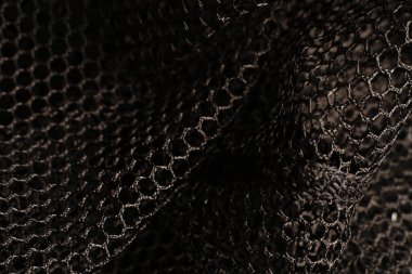 Siyah doku. Siyah bir ağ siyah delikli metal bir masanın üzerine yerleştirilir. Işık parlıyor..