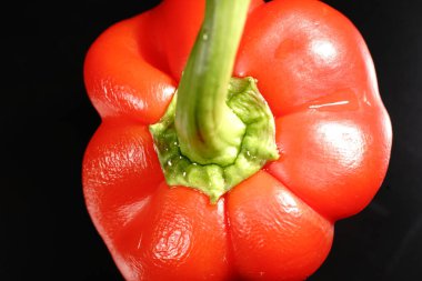 Siyah arka planda yeşil kuyruklu kırmızı tatlı biber. Loş ışıklar. Kapat.