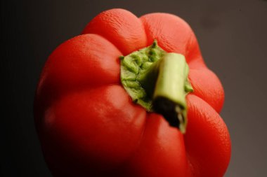 Siyah arka planda yeşil kuyruklu kırmızı tatlı biber. Loş ışıklar. Kapat.