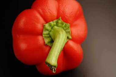 Siyah arka planda yeşil kuyruklu kırmızı tatlı biber. Loş ışıklar. Kapat.