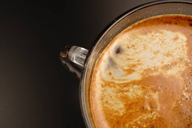 Bir fincan kahve. Karanlık bir arka planda ve yarı karanlıkta. Güzel bir köpük çizimi..