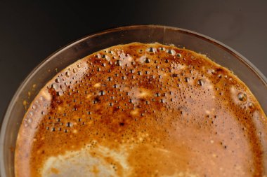 Bir fincan kahve. Karanlık bir arka planda ve yarı karanlıkta. Güzel bir köpük çizimi..