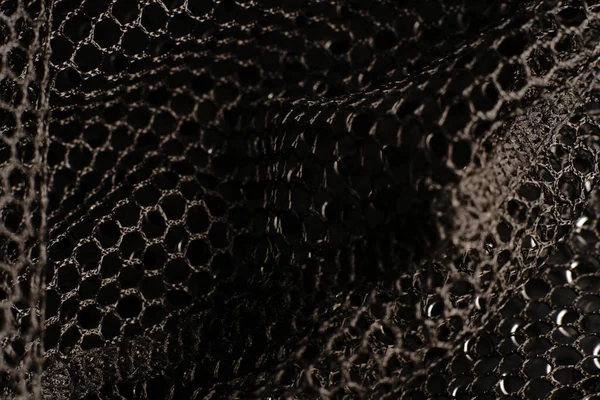 Siyah doku. Siyah bir ağ siyah delikli metal bir masanın üzerine yerleştirilir. Işık parlıyor..