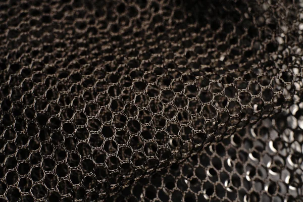 Siyah doku. Siyah bir ağ siyah delikli metal bir masanın üzerine yerleştirilir. Işık parlıyor..