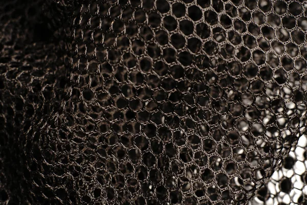 Siyah doku. Siyah bir ağ siyah delikli metal bir masanın üzerine yerleştirilir. Işık parlıyor..