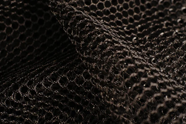 Siyah doku. Siyah bir ağ siyah delikli metal bir masanın üzerine yerleştirilir. Işık parlıyor..