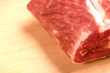 Kırmızı et tahta bir tahtanın üzerinde yatar. Görünür yağ tabakaları ve et dokusu. Domuz eti.
