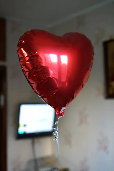 Ett hjärta uppblåst av heliumflugor på ett snöre hemma. En present till Alla hjärtans dag. — Stockfoto