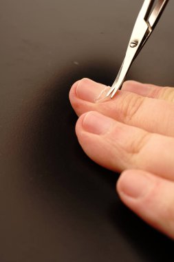 Kadınların elleri siyah arka planda tırnaklarını tırnak makası ile düzeltiyordu. El bakımı.