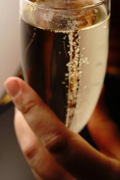 A menina segura uma taça de champanhe com a mão à noite com uma luz agradável. A bebida em si é destacada. — Fotografia de Stock