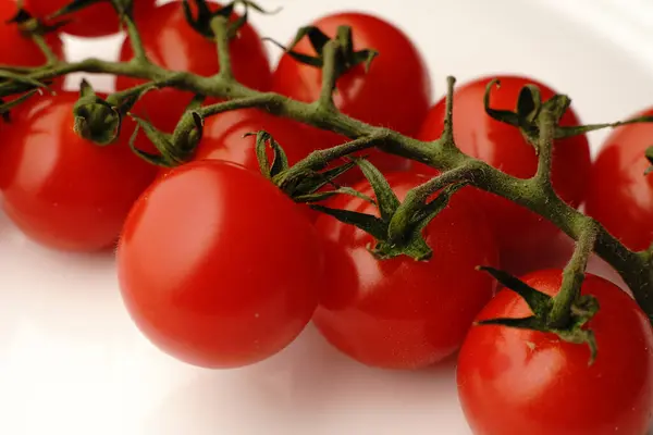 Невеликі червоні помідори на гілці на білій тарілці. дієтичне харчування . — стокове фото