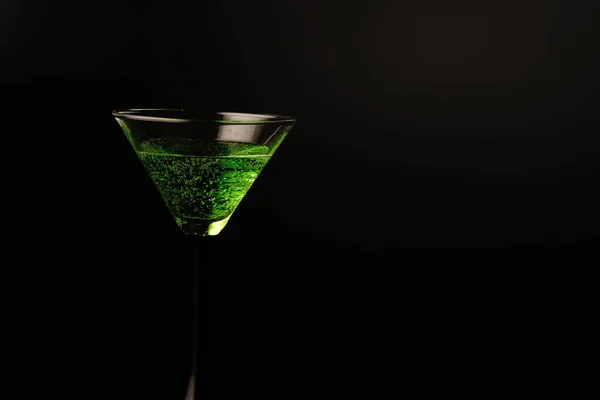 Two glasses with a green cocktail on a black background. One glass is full and the other is empty — Stock Photo, Image