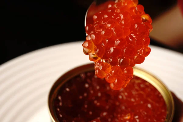 El caviar rojo en un frasco acaba de abrir. Lo tomamos con una cuchara.. — Foto de Stock