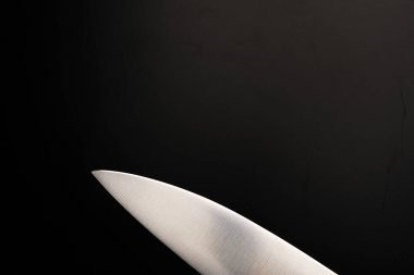 Siyah arka planda büyük bir bıçağın bıçağı. Sönük ışıklar.