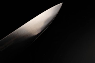 Siyah arka planda büyük bir bıçağın bıçağı. Sönük ışıklar.