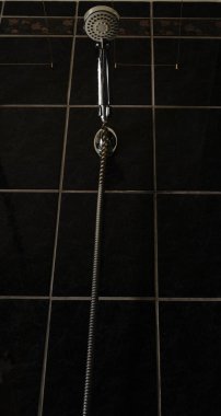 Duş tutacağı banyodaki kürsüde duruyor. Arkaplanda siyah kiremitler.